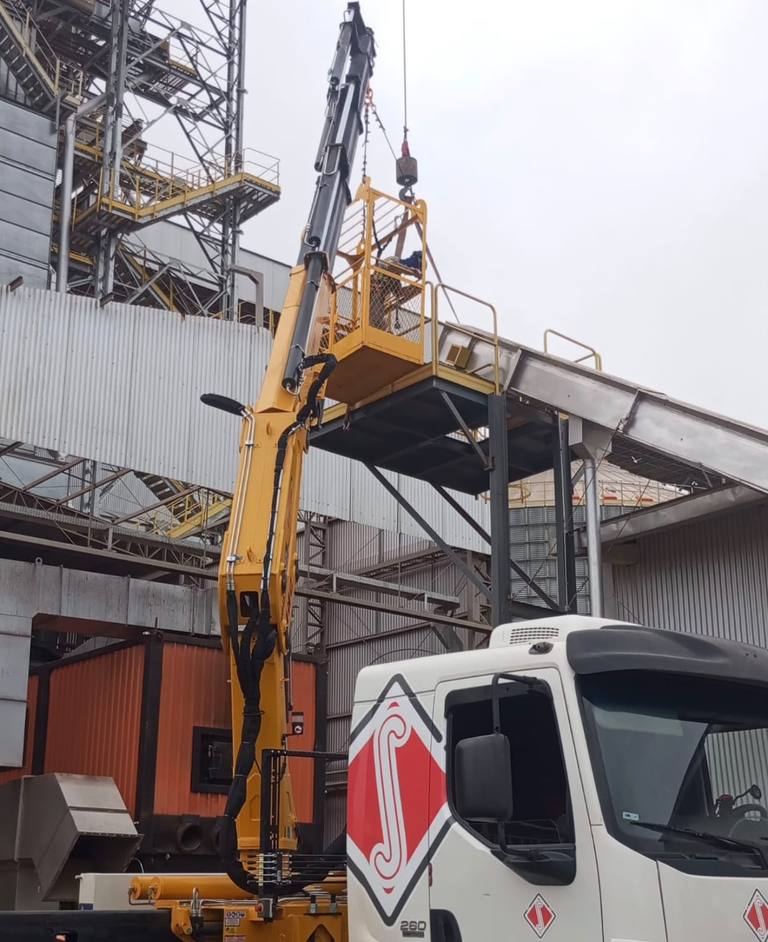 Lança do caminhão munck içando equipamento em indústria com operador